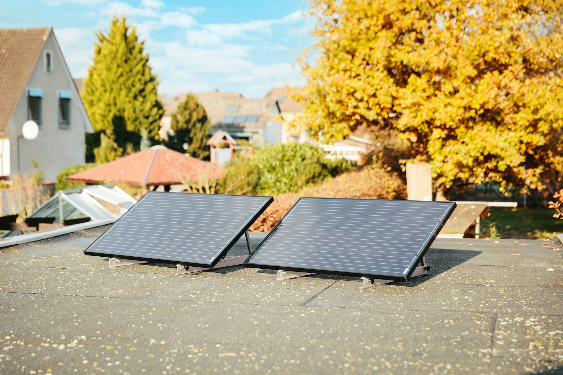 Two solar panels on a rooftop with autumn foliage.